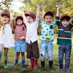 A group of children standing together with their arms up in celebration.