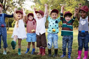 A group of children standing together with their arms up in celebration.